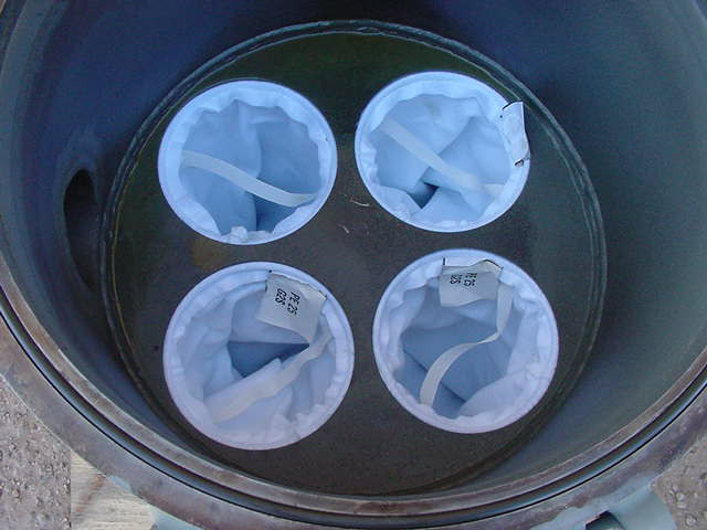Industrial filtration system featuring four filter bags inside a cylindrical housing, designed for efficient liquid filtration in pipeline applications.