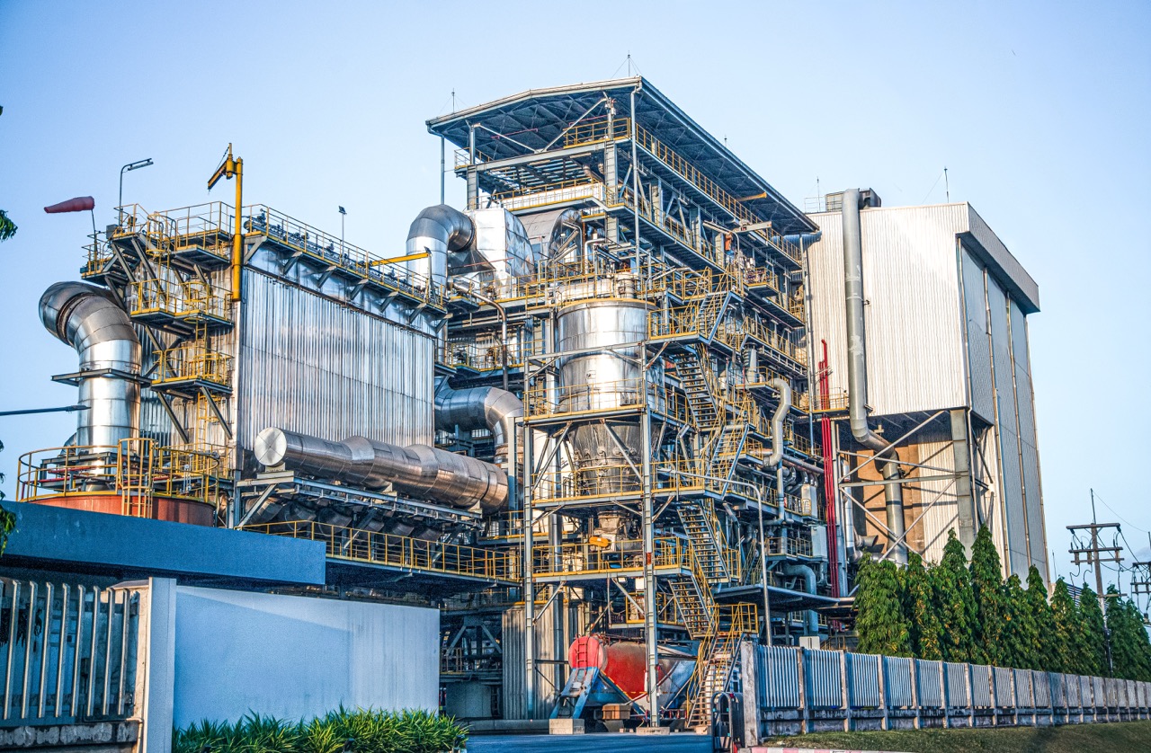 Industrial power plant with complex piping and structures, showcasing modern engineering and energy production technology against a clear blue sky.