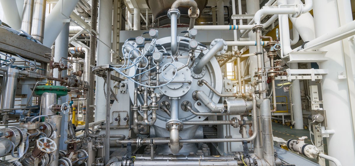 Industrial machinery with complex piping and valves, showcasing a large mechanical system in a manufacturing facility. The image highlights the intricate network of tubes and gauges essential for operational efficiency in industrial processes.