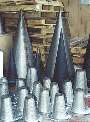 Metal cone strainers of various sizes arranged in a warehouse, designed for startup and temporary pipeline protection.