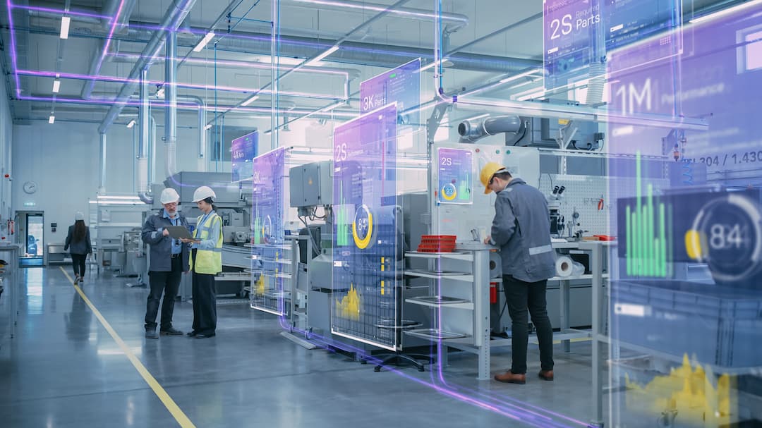 Two engineers discussing data in a modern manufacturing facility, featuring digital displays with performance metrics and analytics. The environment showcases advanced machinery and smart technology integration, emphasizing efficiency and innovation in industrial processes.