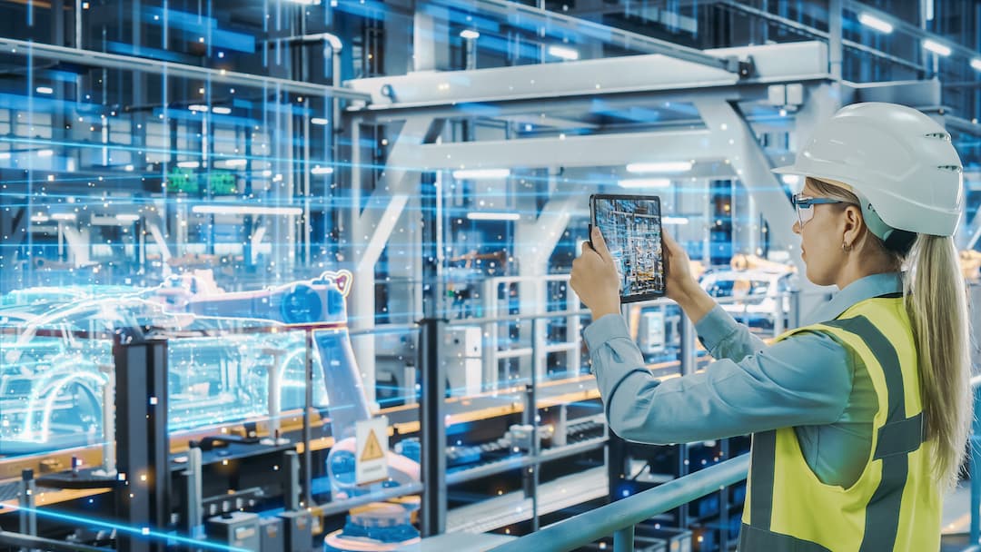 Woman in safety gear using a tablet to monitor advanced manufacturing processes in a high-tech factory, with digital overlays of machinery and automation.