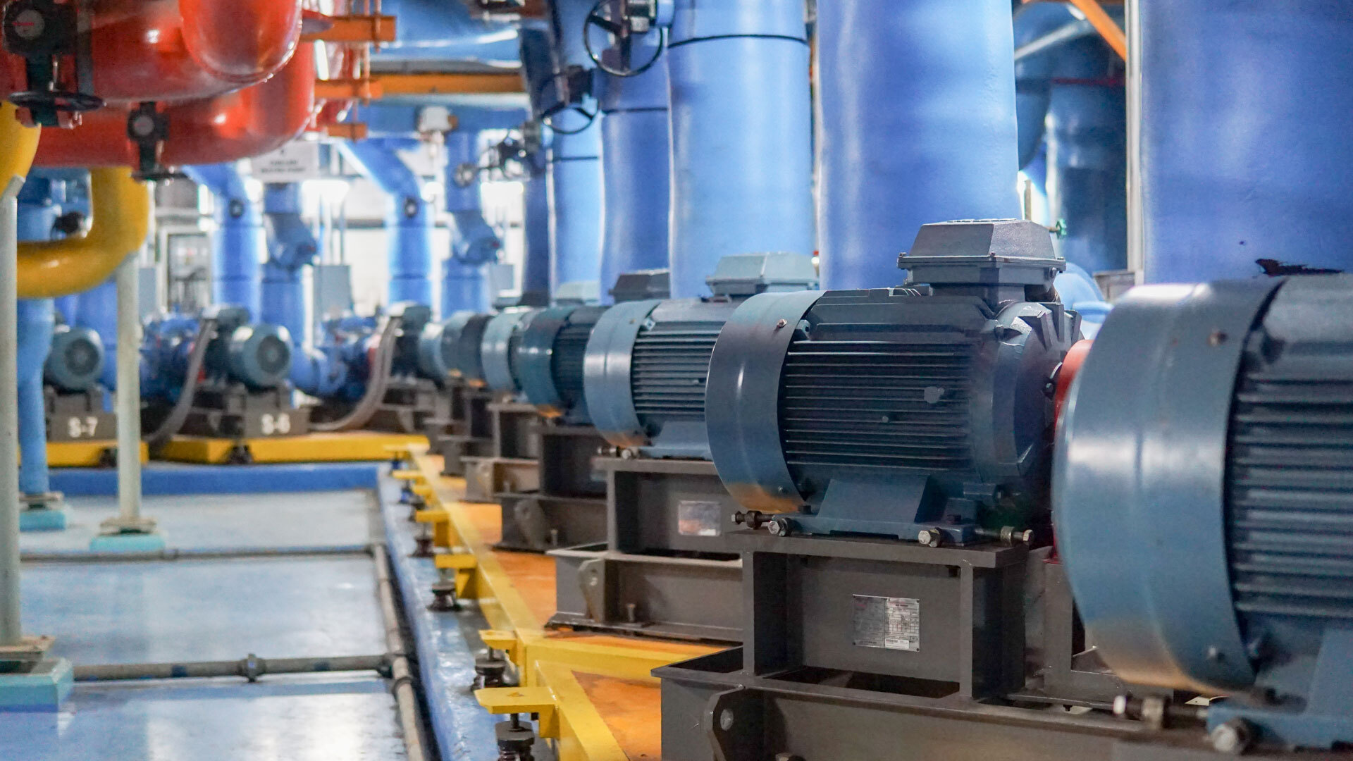 Industrial setting featuring multiple electric motors and pipes, highlighting machinery used for water or fluid management.