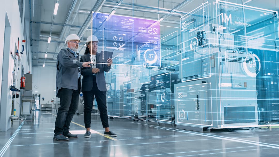 Two professionals in hard hats examine digital maintenance data on a tablet in a modern industrial facility, showcasing advanced technology and digital interfaces for equipment performance monitoring.