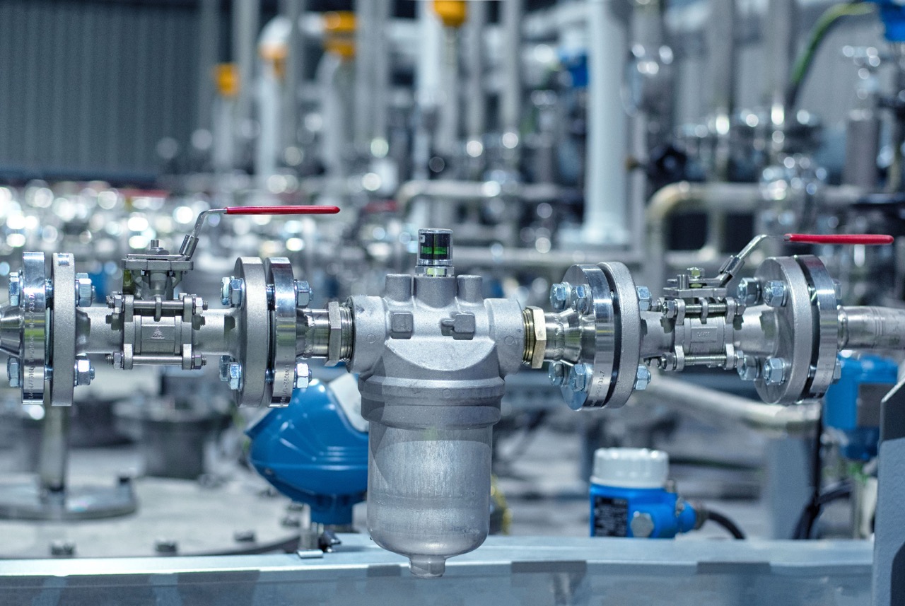 Industrial valve system with stainless steel components and a pressure gauge, showcasing advanced engineering in a manufacturing facility.