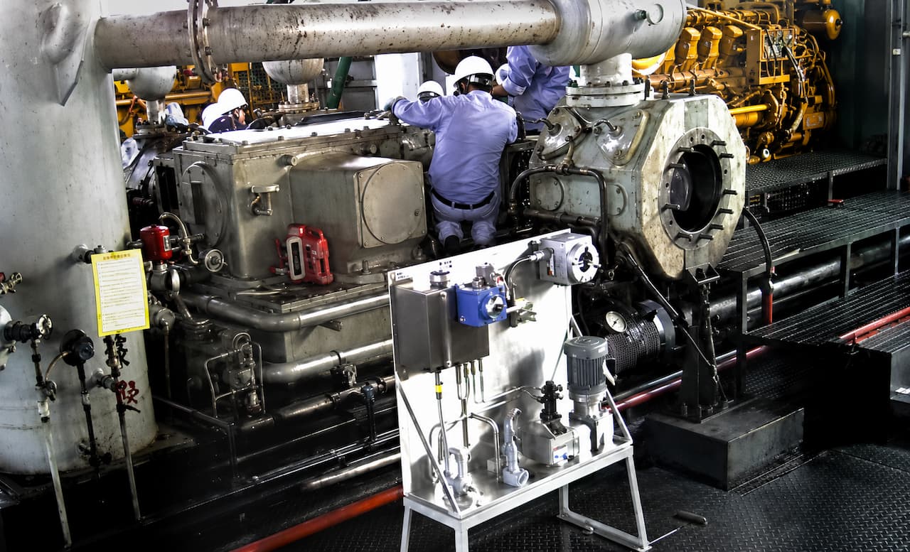 Technicians performing lubrication systems repair on industrial machinery, showcasing a detailed view of the equipment and tools used in the process.