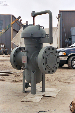 Gas basket strainer for industrial applications, featuring a robust design with flanged connections and a top-mounted inlet. The strainer is shown in an outdoor setting, highlighting its durable construction suitable for filtering gas and protecting pipelines from debris.