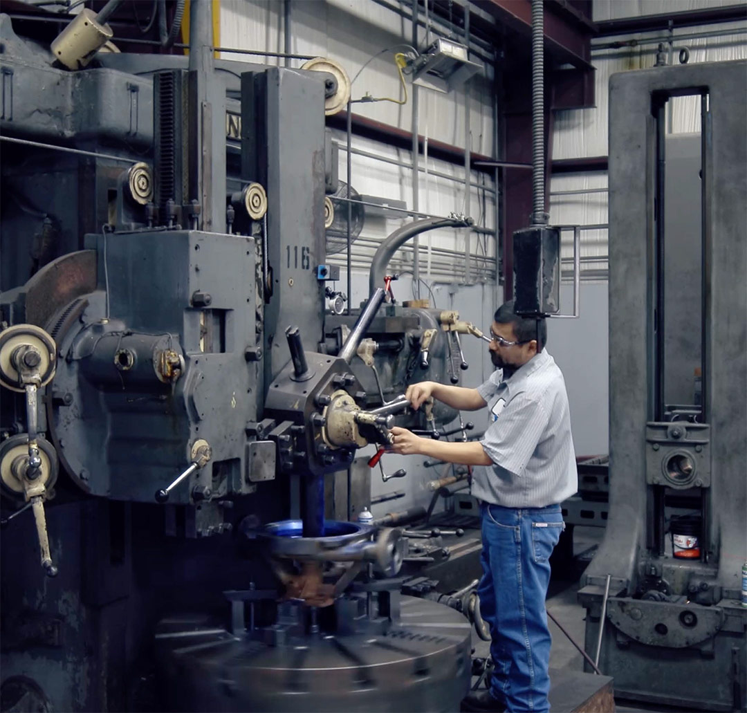 Technician operating industrial rotating equipment in a Texas workshop, focusing on maintenance and repair of machinery components.